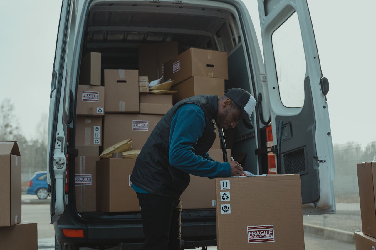 Delivery man sorting packages in van, organizing shipments for distribution.